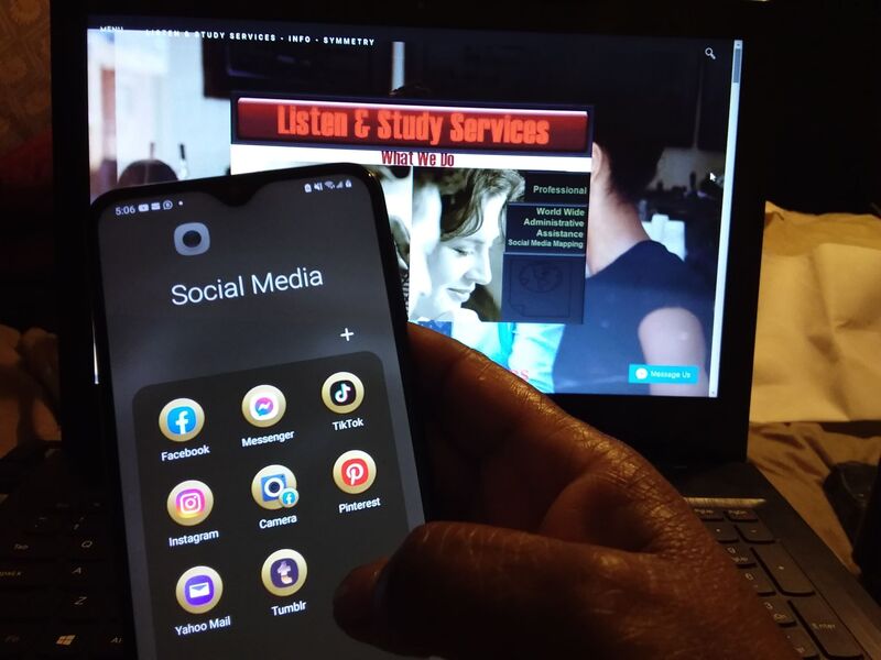 A hand holds cell phone that reads, "Social Media" folder. Image of a computer in the background reads, "Listen & Study Services"!